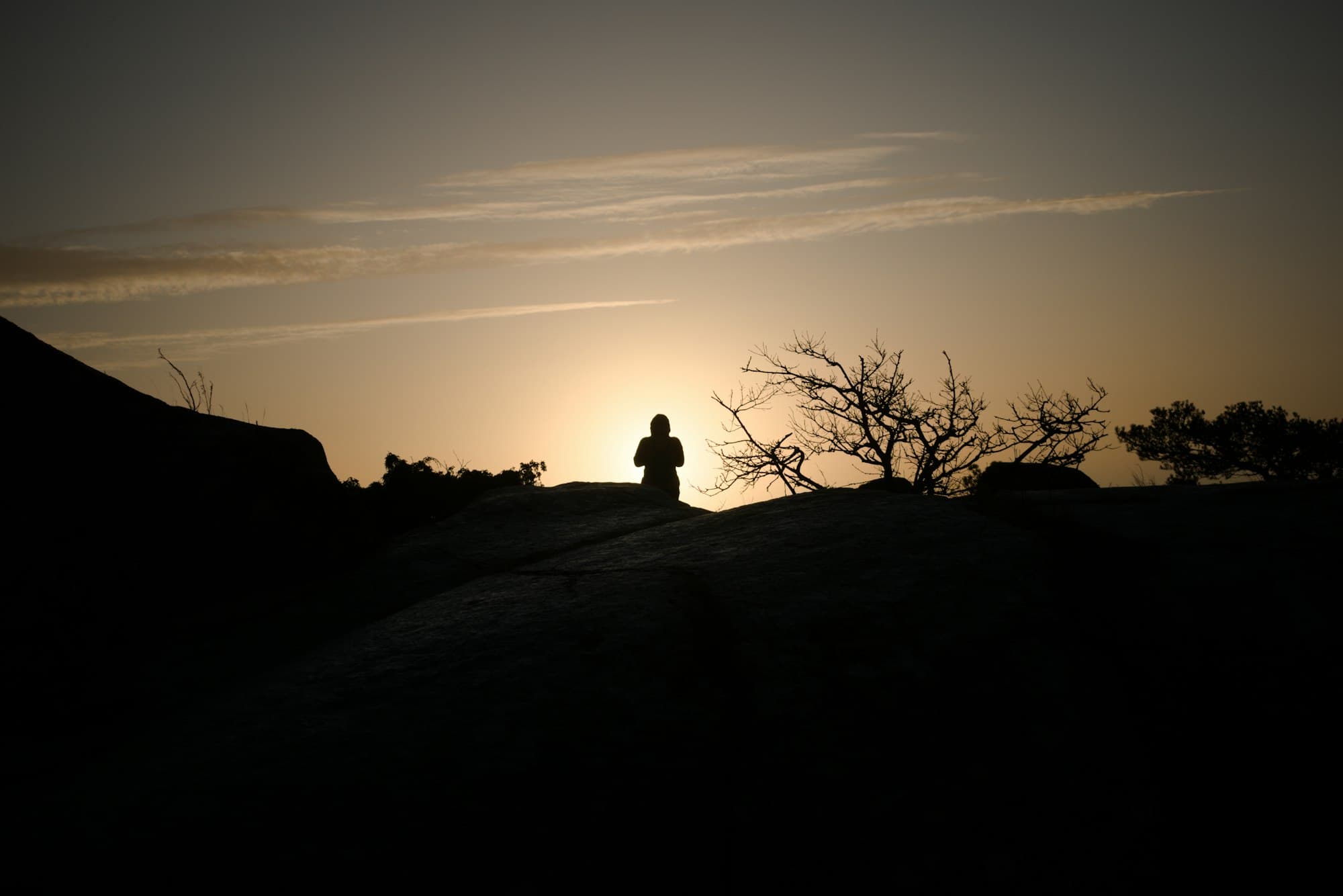 A silhouette sitting quietly at sunset